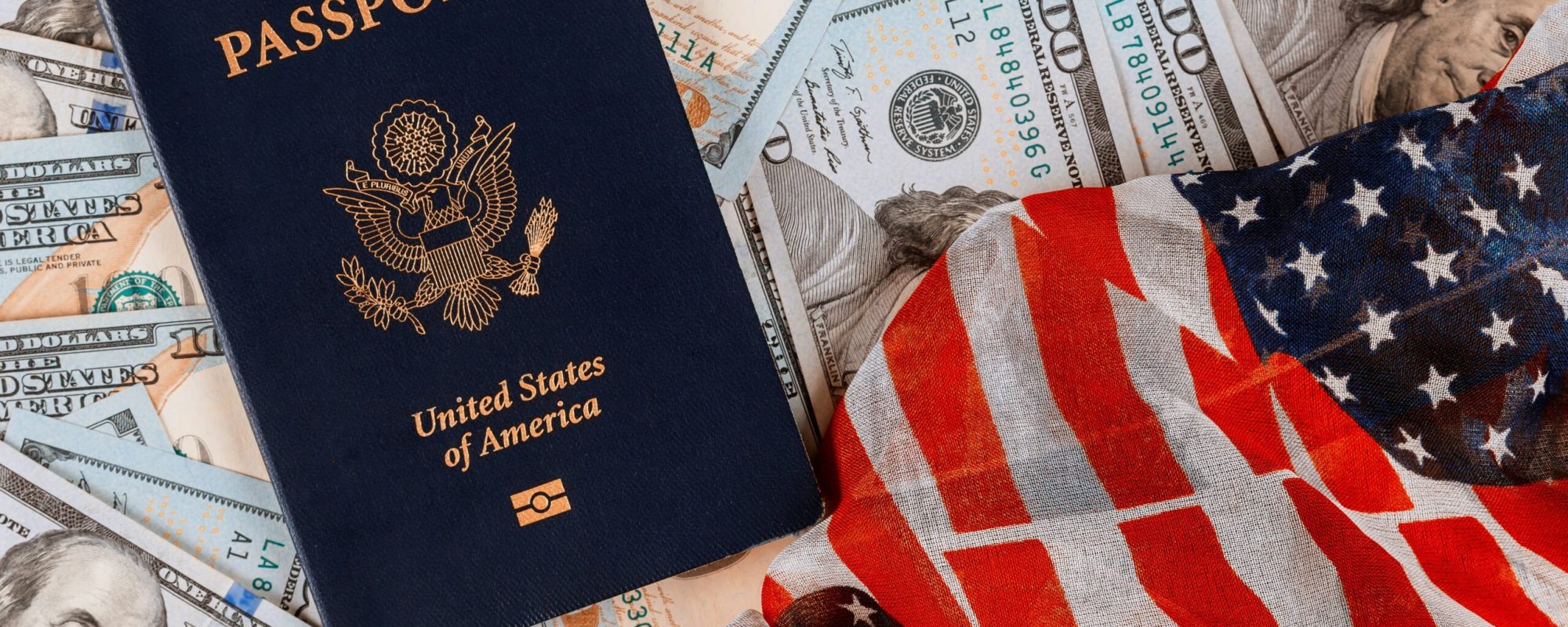 Patriotic USA passport on top of a pile of one hundred US banknote currencies on American flag